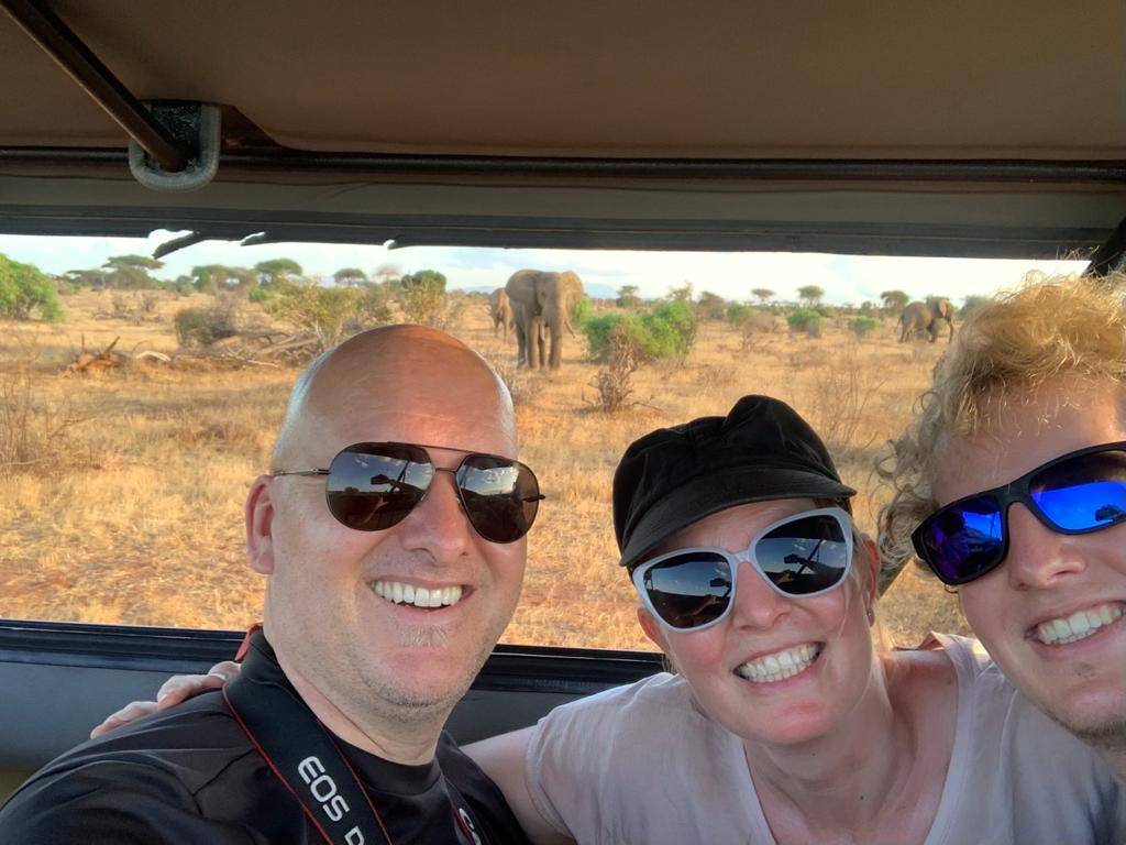 Safari group selfie with elephants in the background